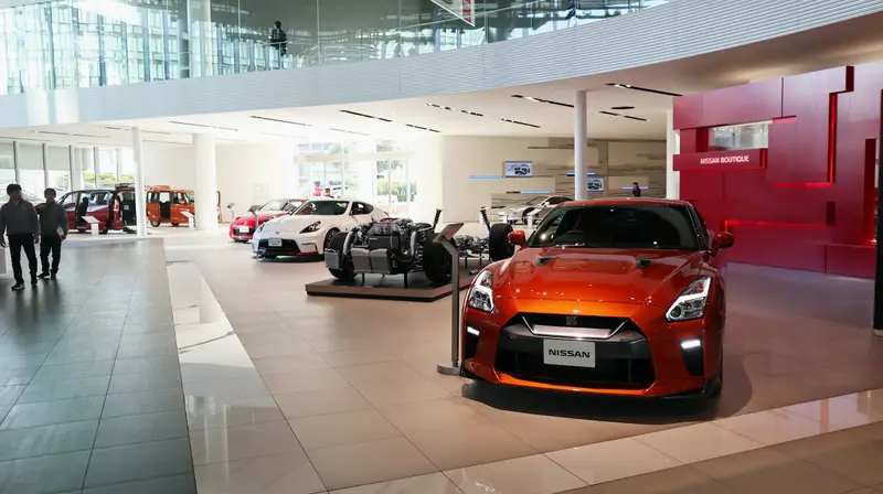 A bright car showroom with an orange sports car on display